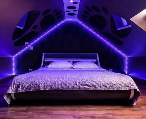 a bedroom with a bed with purple lights on it at Spa love room in Donges