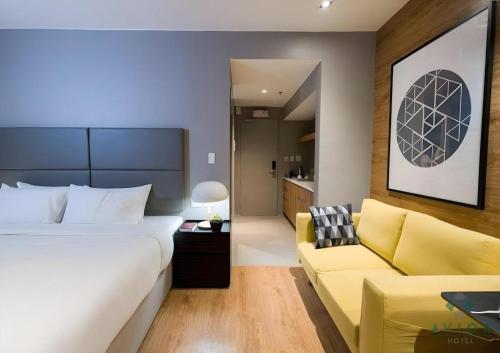 a bedroom with a large bed and a yellow couch at Avior Hotel in General Santos