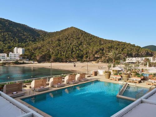 a swimming pool with lounge chairs and a beach at Mondrian Beach Lifestyle Resort By Accor in Cala Llonga