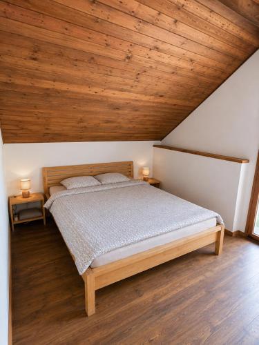 a bedroom with a large bed with wooden ceilings at Medaus slėnis in Šilinė