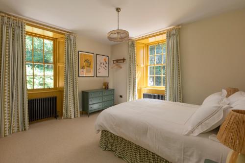 a bedroom with a bed and two windows at The Lodge at Dabton House in Carronbridge