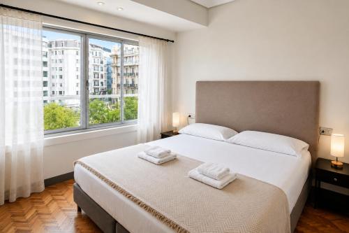 a bedroom with a bed and a large window at ZUBIETA by SWEET HOME SAN SEBASTIAN in San Sebastián
