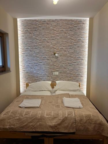 a bed in a room with a brick wall at Dom Wypoczynkowy Maniek in Białka Tatrzańska