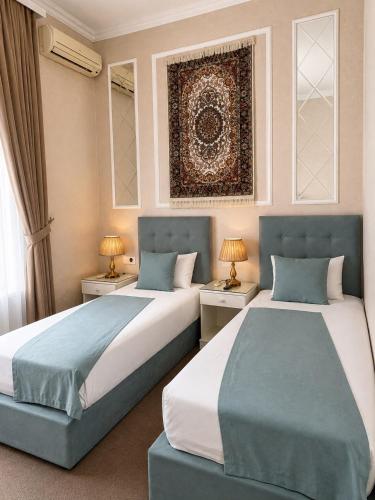 two beds in a room with two tables and two lamps at La Casa Boutique Nizami in Baku