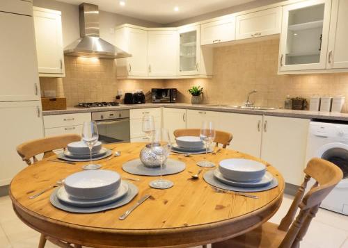a kitchen with a wooden table with plates and wine glasses at The Old Reading Rooms Linton in Linton
