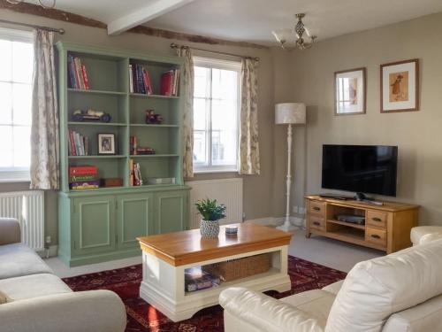a living room with a couch and a table and a tv at The Old Reading Rooms Linton in Linton