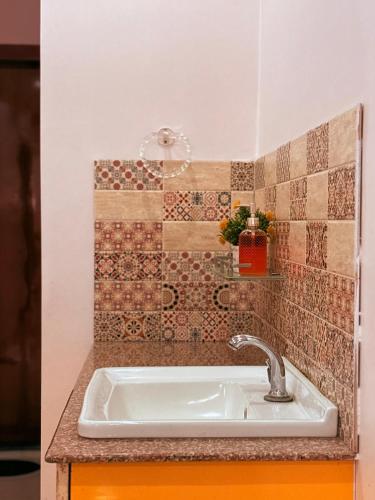 a sink in a bathroom with a tiled wall at Mi casa homestay in Guwahati