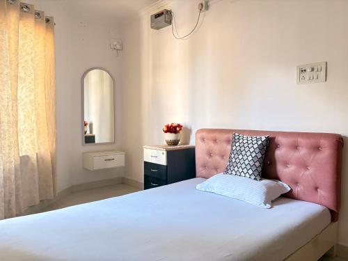a bedroom with a bed with a pink headboard and a mirror at Mi casa homestay in Guwahati