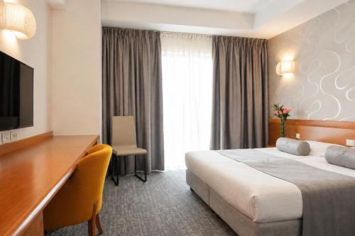 een hotelkamer met een bed, een bureau en een televisie bij Hotel Venko in Dobrovo