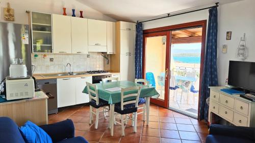a kitchen with a table and a kitchen with a balcony at CASA MAESTRALE - Vista mare Pittulongu - Sardegna - IUN R2217 in Olbia