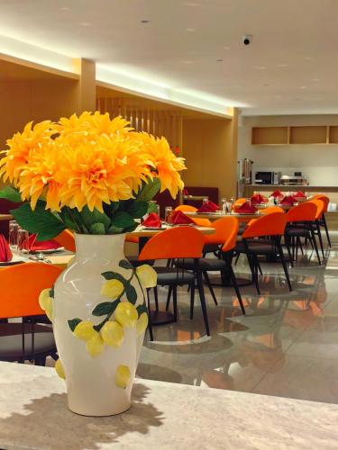 a vase filled with yellow flowers sitting on a table at Ivy Hotel Lagos Ikeja in Hausa