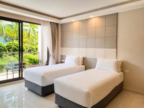 two beds in a room with a window at Sunset Beach Hotel - Adults Only in Haad Rin