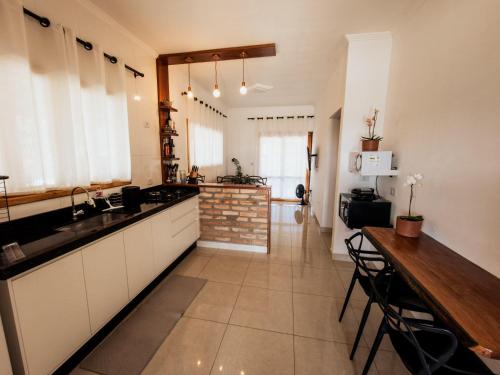 a large kitchen with a counter and a table at Chalé 1 Refúgio do Sol Piscina com Vista para Montanas in Socorro