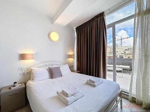 a bedroom with a white bed and a large window at Ta Gianni Guest House Sliema in Sliema