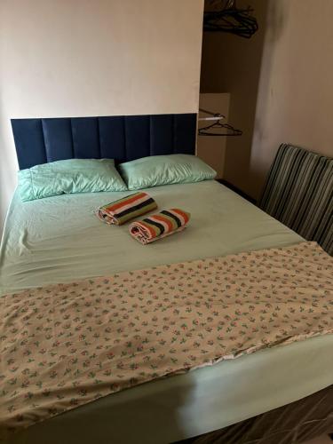 a bed with a blue headboard and two towels on it at casa tres quartos condominio aeroporto lazer praias mercados a poucos minutos in Salvador
