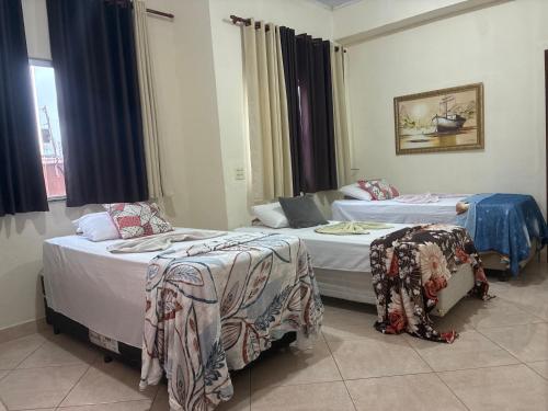 two beds in a hotel room withskirts at Hospedagem da Néli 2 in Aparecida