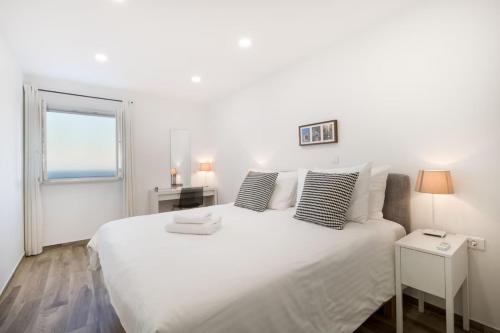 a white bedroom with a large white bed with pillows at Modern Penthouse Split with Jacuzzi & Terrace in Split