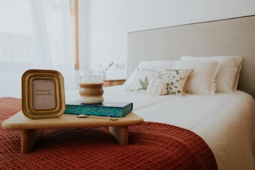 a bed with a table with a clock on it at O Recuncho do Castelo in Ribadavia