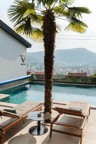 a palm tree and lounge chairs next to a swimming pool at Villa View Mostar with Heated Pool & Jacuzzi in Mostar