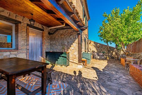 a patio with a wooden table and a stone wall at El Regreso in Jarilla
