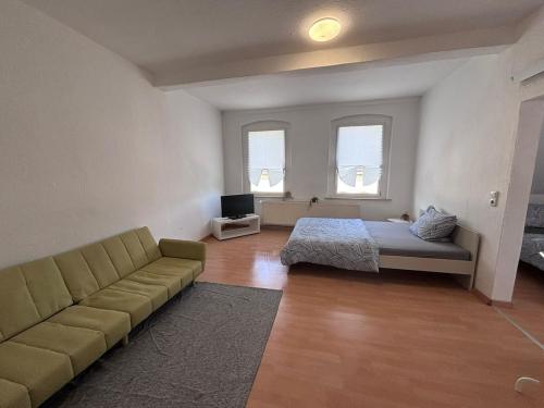 a room with a couch and a bed and windows at Comfortable and functional apartment in Kretzschau