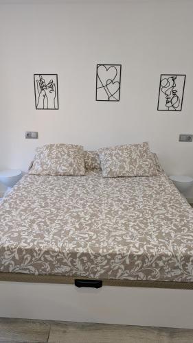 a bed in a bedroom with three pictures on the wall at Praciña do olvido in Cee
