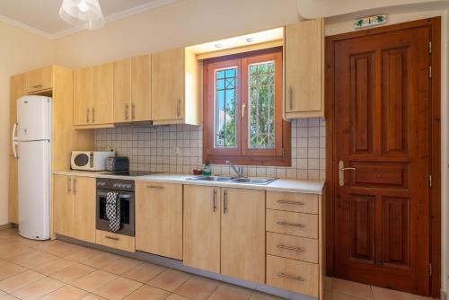 a kitchen with wooden cabinets and a sink and a refrigerator at Villa Katerina BBQ & pool! in Metaxáta