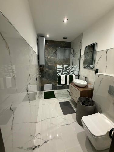 a white bathroom with a sink and a toilet at Guest Apartman in Tiszakécske