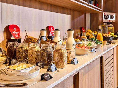 a buffet with many jars of food on a counter at ibis Madrid Norte Las Tablas in Madrid
