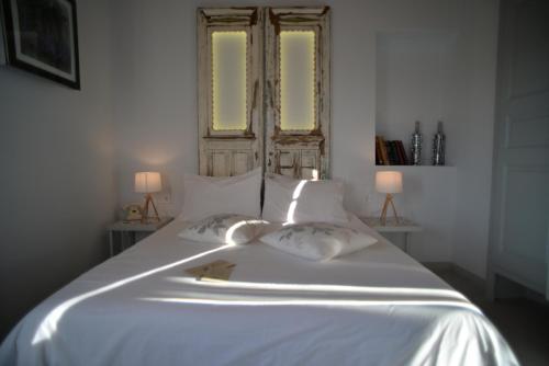 a bedroom with a white bed with two windows at 1901 Hermoupolis in Ermoupoli