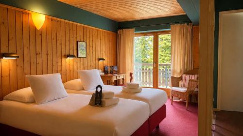 a hotel room with two beds and a balcony at Plein Ciel - Hôtel d'altitude à 1800m in Champéry