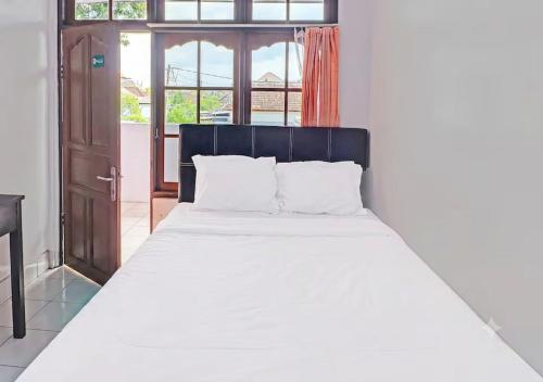 a bedroom with a large bed with white sheets at Ari Gusti Residence in Dalung