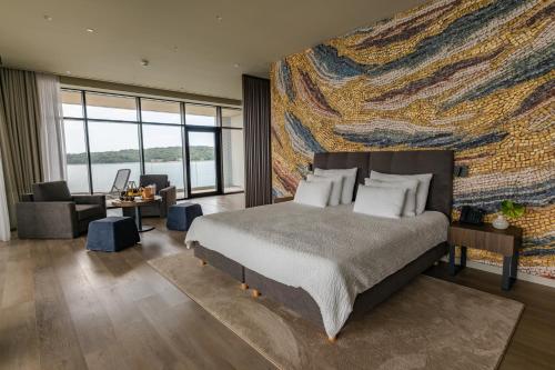 a bedroom with a bed and a large painting on the wall at Monumenti Heritage Hotel&Resort in Pula