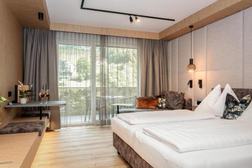 a hotel room with a large bed and a balcony at Hotel Almrausch in Saalbach-Hinterglemm