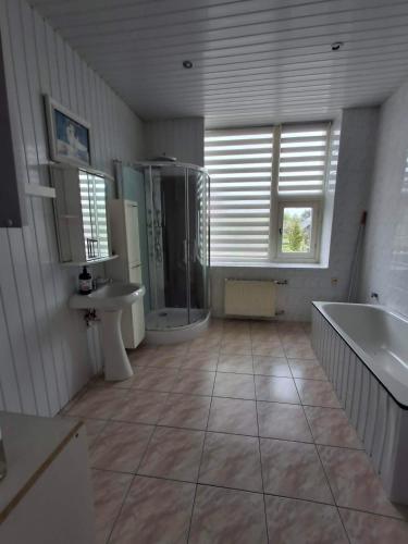a large bathroom with a tub and a sink at Svečių namai miestelio centre in Mosėdis