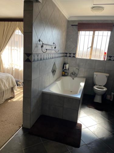 a bathroom with a bath tub and a toilet at Diamo Guest House in Roodeplaat