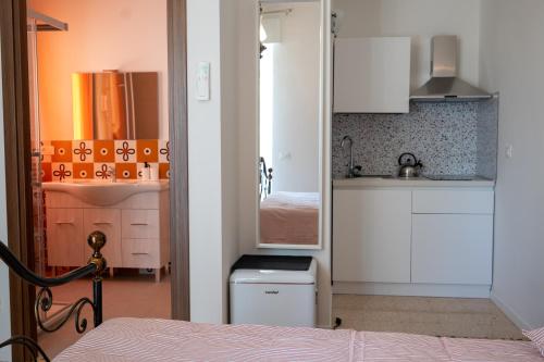 a small kitchen with white cabinets and a bed at SanPatrizio Guest House in Torre San Patrizio