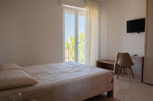a bedroom with a bed and a desk and a window at SanPatrizio Guest House in Torre San Patrizio