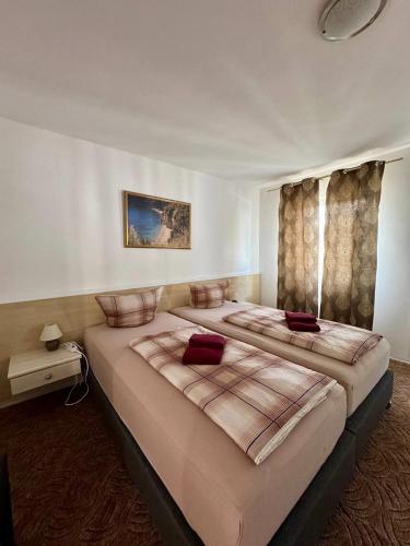 a bedroom with two beds with red pillows on them at Hotel Gästehaus Altena in Altena