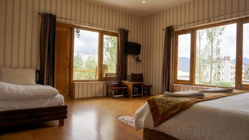 a bedroom with two beds and a large window at Green View Hotel in Leh