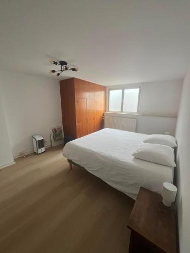 a bedroom with a large white bed and a window at Maison Agathe in Brussels