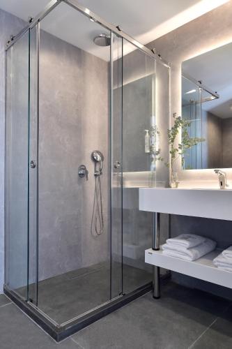 a glass shower in a bathroom with a sink at Acropolis Lumina in Athens