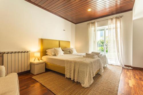 a bedroom with a bed and a large window at Casa da Palmeira in Sesimbra
