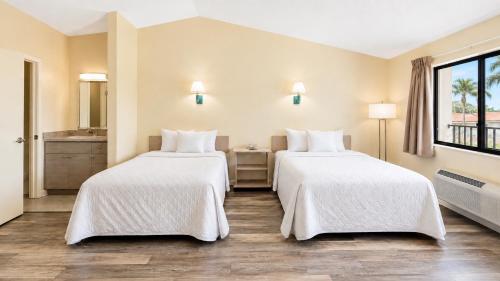 a hotel room with two beds and a window at Royal Inn Hotel in Royal Palm Beach