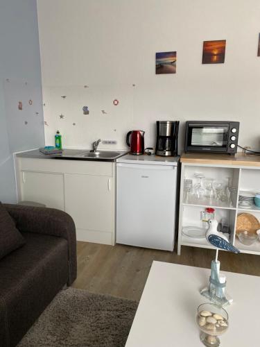 a kitchen with white cabinets and a microwave at Pension Dünenhaus in Zempin