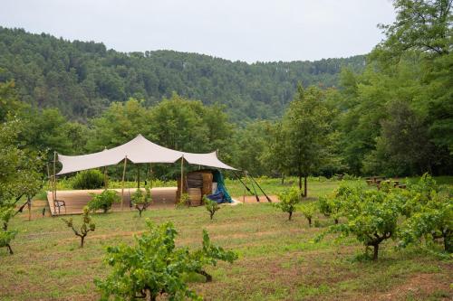 a tent in the middle of a field with trees at Camping Ushuaïa Villages Les Cruses in Ribes