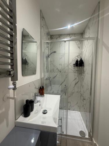 a white bathroom with a shower and a sink at CoolSideOfThePillow in Swindon