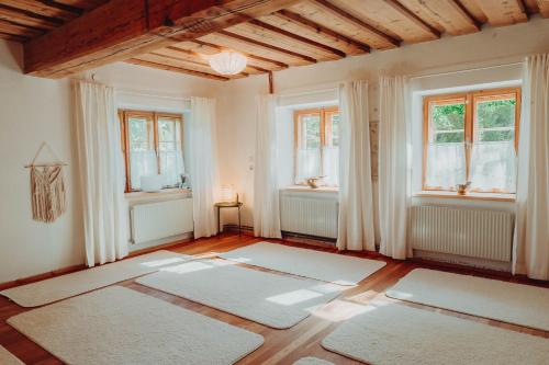 a room with white rugs on the floor and windows at Der Yogahof in Tratten