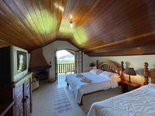 a large bedroom with two beds and a television at Pousada Bela Mauá in Itatiaia