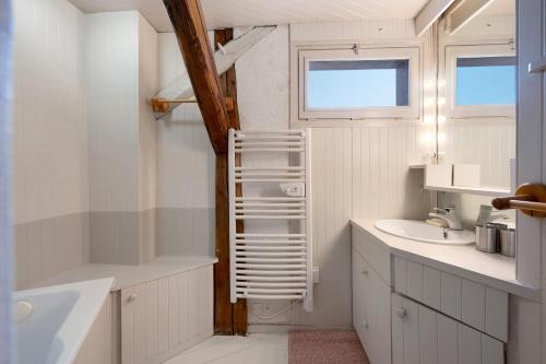 a white bathroom with a sink and a bath tub at Chalet La Grange Courchevel in Courchevel